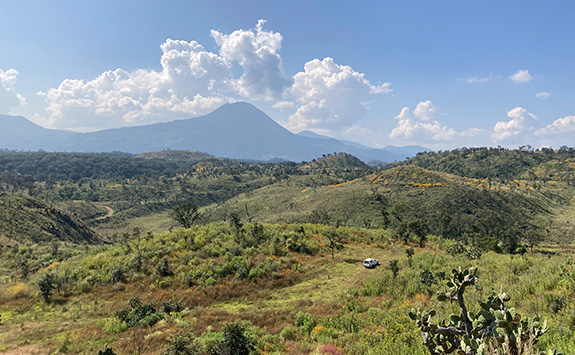 View of landscape in Zacapu with green undulating fields, blue sky and a mountainous area in the background